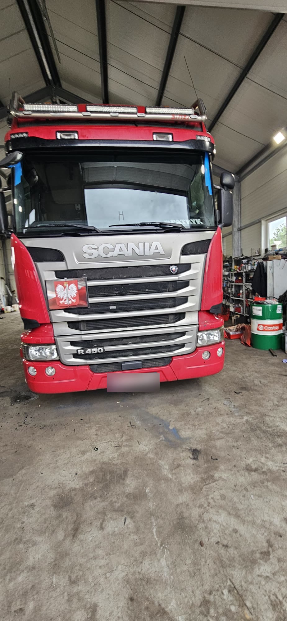Scania R450 z nową szybą czołową zabezpieczoną taśmą w hali serwisowej